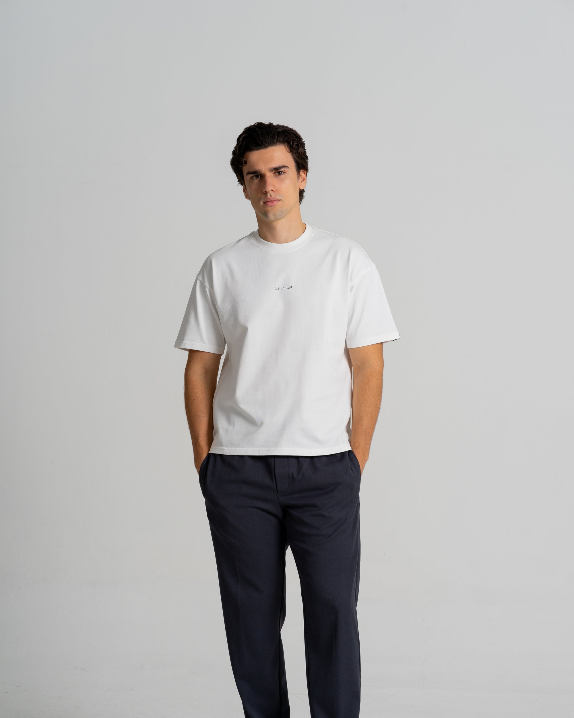 Male model wearing premium white oversized Le Lemud t-shirt with navy trousers, front view